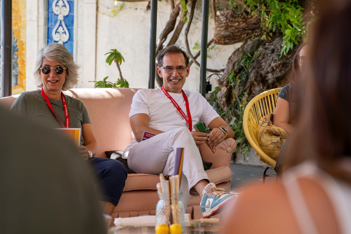 Gus and Graça smiling on a pink sofa, leading a conversation at Lisboa 2036